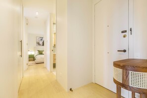 Ein Flur, der in ein Schlafzimmer mit einem Bett, einem Nachttisch und einer Türklinke führt.