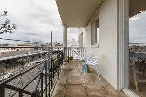 Ein Balkon mit Blick auf die Straße, ein weißer Stuhl und ein Tisch.