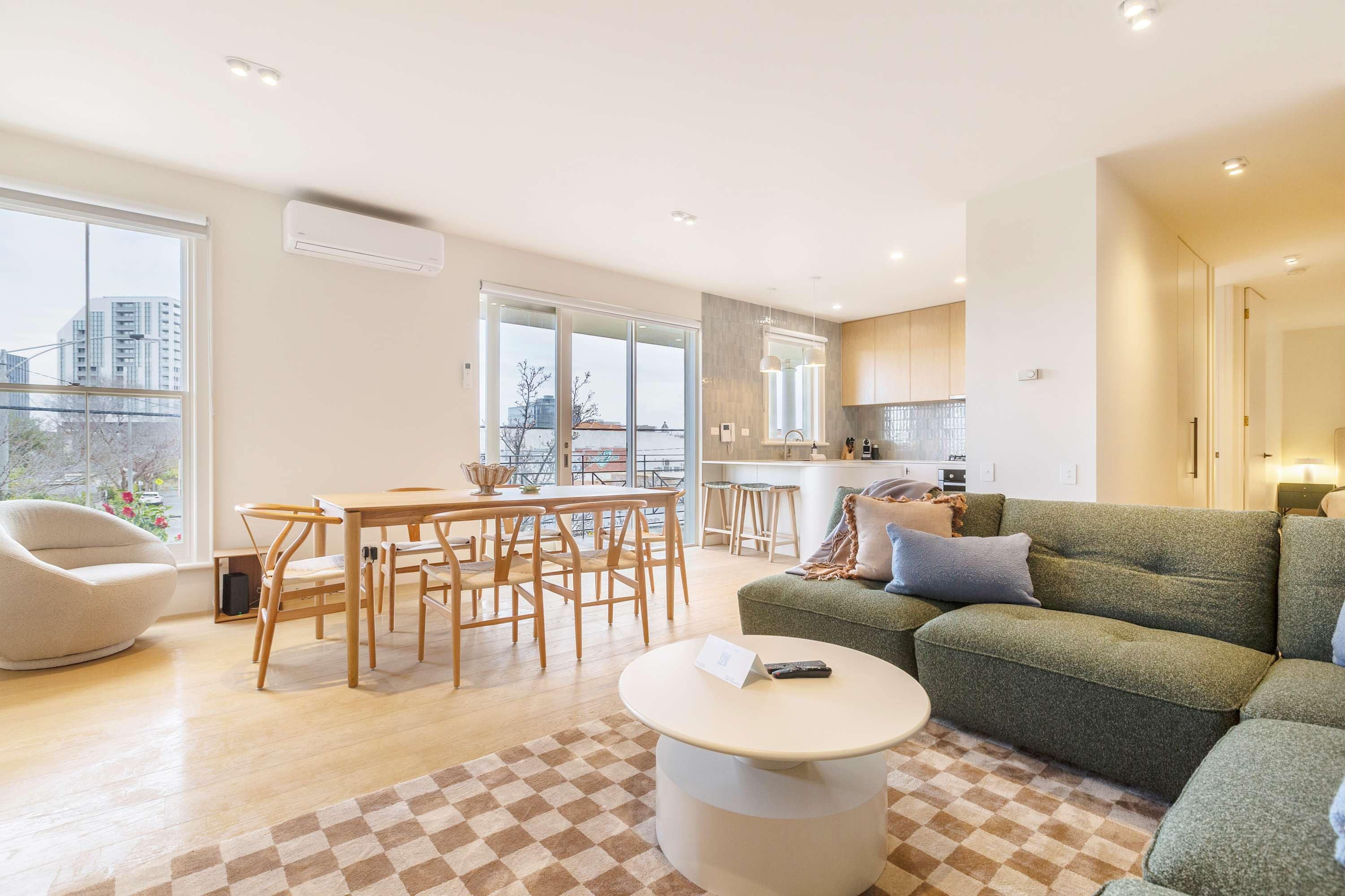 Un salon moderne avec un coin repas, un canapé vert et un sol à carreaux.