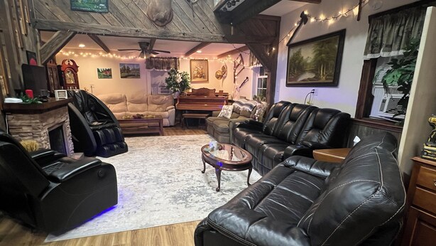 A cozy living room with leather sofas, a fireplace, and string lights.