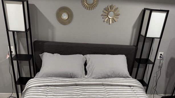 Ein Bett mit gestreiftem Bettbezug, zwei Nachttischlampen und Wanddekoration.