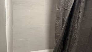 Ein Badezimmer mit Duschvorhang, Toilettenpapier und gefliesten Wänden.