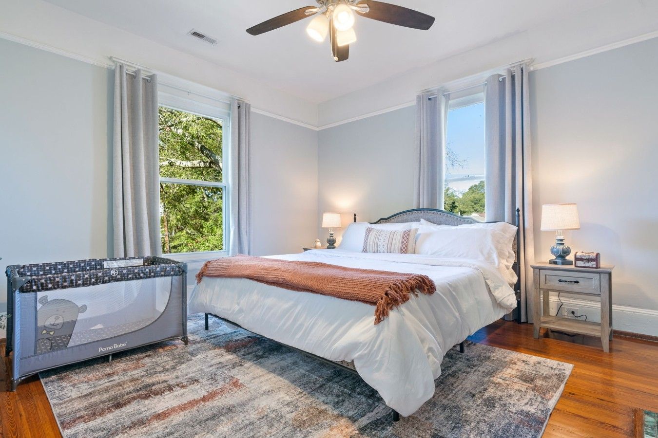 A bedroom with a bed, bedside tables, a ceiling fan, and a window with curtains.