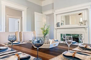 A dining room with a wooden table set for a meal, a fireplace, and a mirror above it.