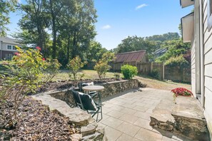 A patio with stone flooring, a small round table, and two chairs.