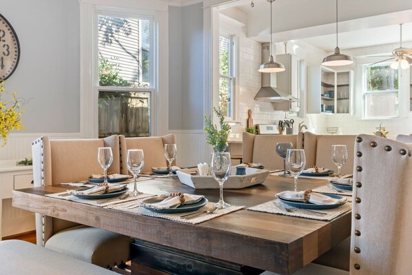A dining area with a wooden table set for four, surrounded by cushioned chairs.