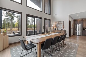 A modern kitchen with stainless steel appliances, a dining area with a wooden table and chairs, and large windows offering a view of the outdoors. - Spacious 4-bedroom house in tranquil Lead with AC and game room (Lead)