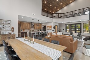 A spacious living area with a dining table, sofas, and a kitchen in the background. - Spacious 4-bedroom house in tranquil Lead with AC and game room (Lead)
