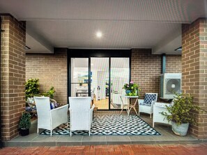 A covered outdoor seating area with brick walls, a patterned floor, and potted plants. - Lovely home in Crangan Bay, between Swansea and  lake Munmorah. (Crangan Bay)