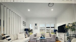 Ein Wohnzimmer mit Sofa, Sesseln, Couchtisch und Fernseher.