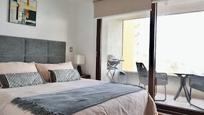 Une chambre d’hôtel avec un grand lit, un bureau et un balcon équipé de chaises.