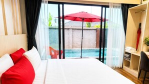 Habitación de hotel con cama, un paraguas rojo, vista a la piscina y un escritorio con silla.