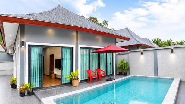 Una casa moderna con piscina, sillas rojas y un porche cubierto.