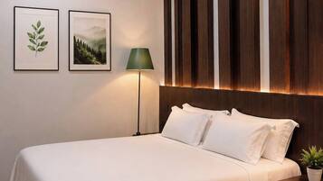 A neatly made bed with white linens, a bedside lamp, and a small potted plant.