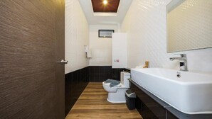 Un baño moderno con una bañera blanca grande, un inodoro y un espejo sobre el lavabo.