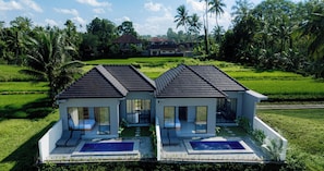 Una villa moderna con dos habitaciones, piscina y vistas a un paisaje verde exuberante.