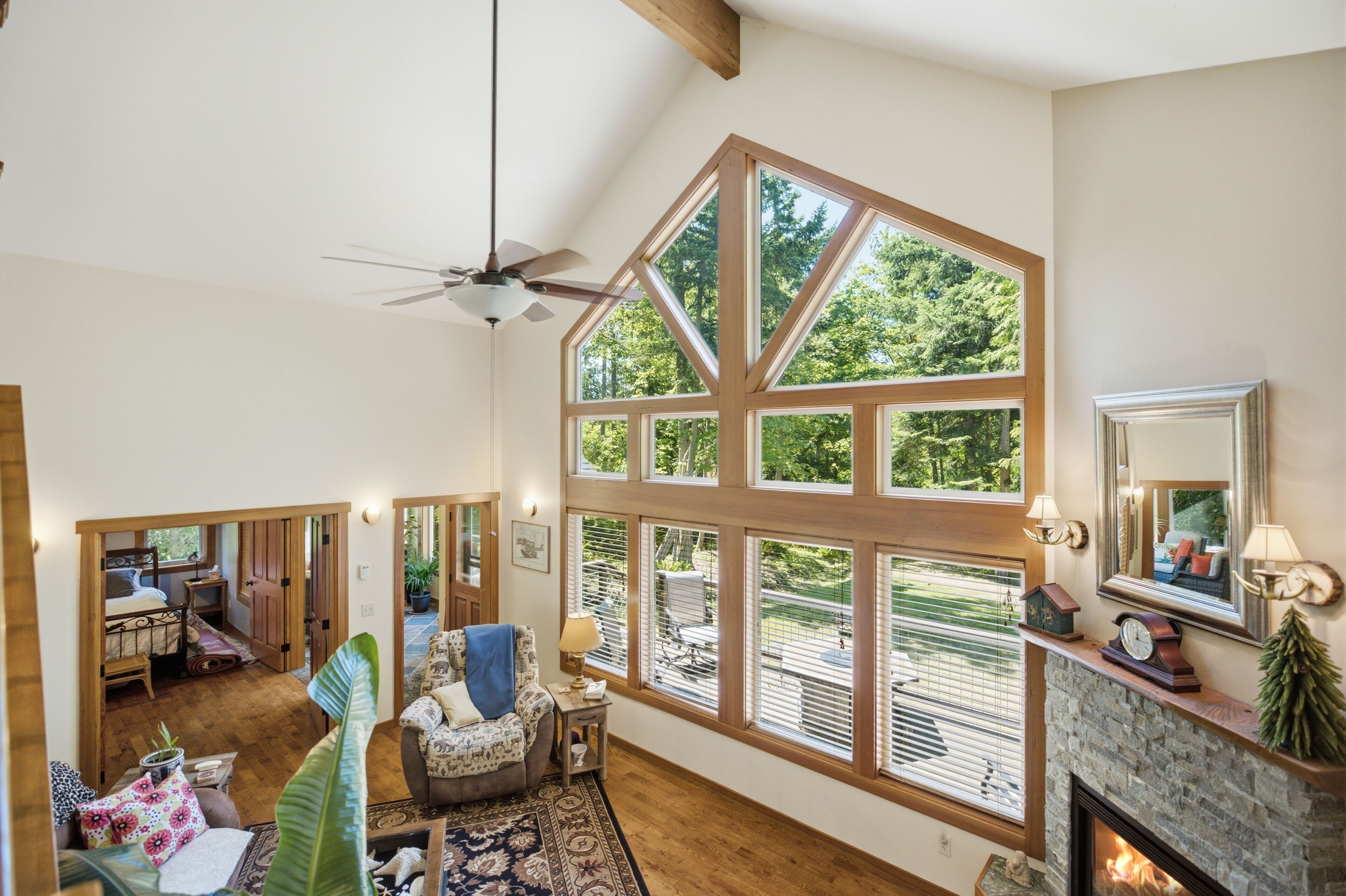 A spacious room with a large window, a fireplace, and a ceiling fan.