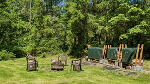 Un espace extérieur verdoyant, avec des chaises en bois et un foyer.