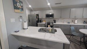 Una cucina moderna con piano di lavoro in marmo, elettrodomestici in acciaio inossidabile e mobili in tinta grigio.
