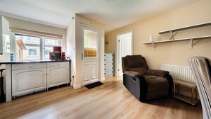 A modern kitchen with white cabinets, a coffee machine, and a chair. - Studio Retreat Sleeps 1 - WiFi & Parking (Cambridge)