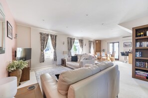A modern living room with a sofa, a television, and a bookshelf. - 2-Bed Cottage Devon/Cornwall border - Dog-friendly (Newbridge, Gunnislake)