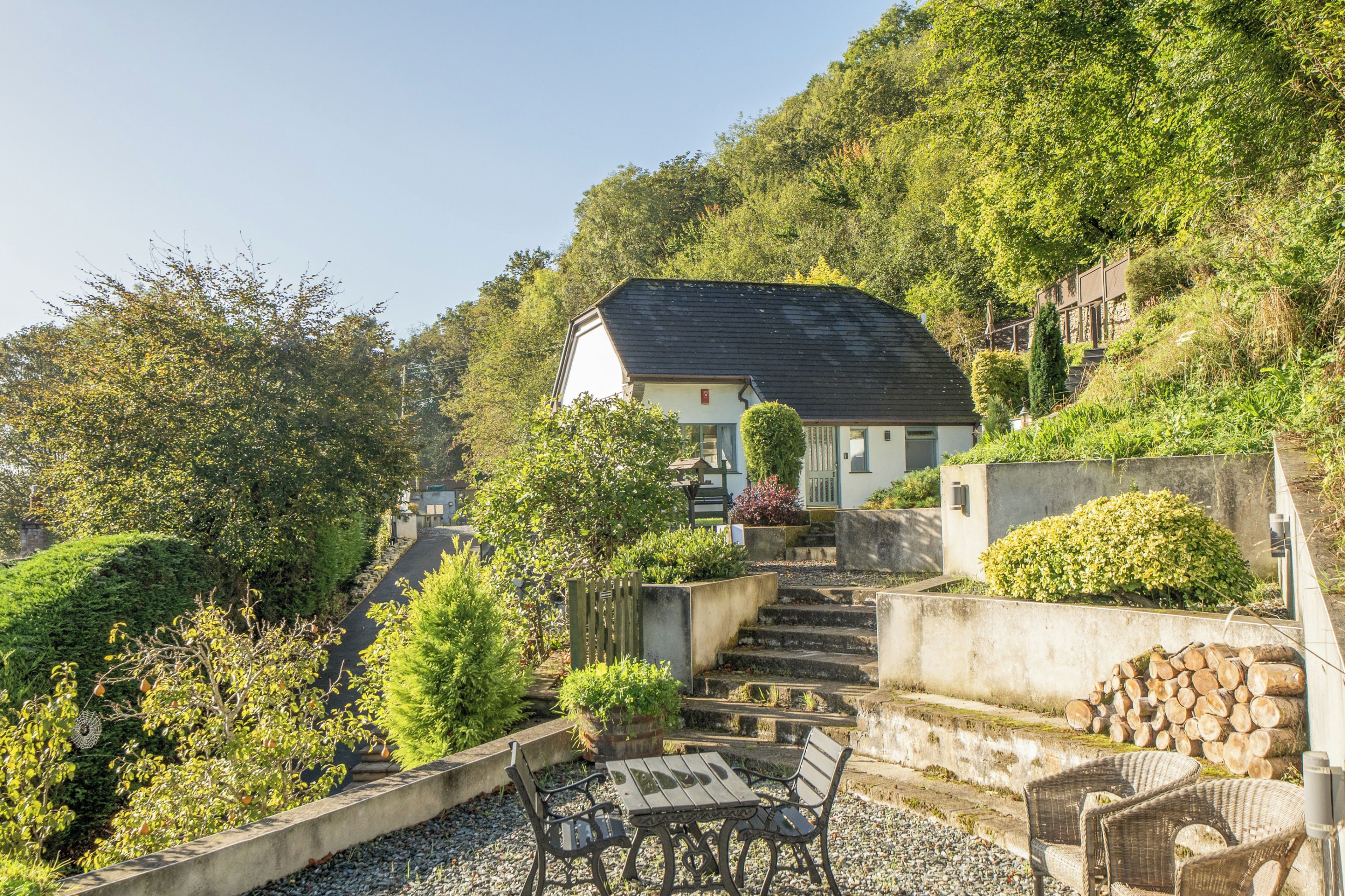A hillside property with a house, outdoor seating, and a staircase leading up.