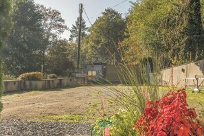A gravel parking area with a concrete wall, a building with a flat roof, and dense foliage in the background. - 2-Bed Cottage Devon/Cornwall border - Dog-friendly (Newbridge, Gunnislake)