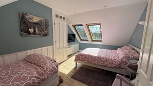 Et soveværelse med to senge, et vindue, et billede og en garderobe.