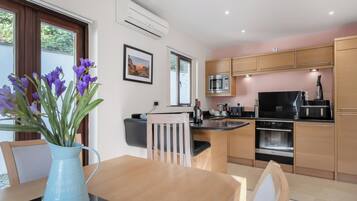 A modern kitchen with a dining area, featuring a built-in microwave, oven, and a coffee machine.