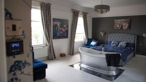 Ein Schlafzimmer mit einer großen Badewanne, einem Bett mit blauer Bettwäsche und zwei Bildern an der Wand.