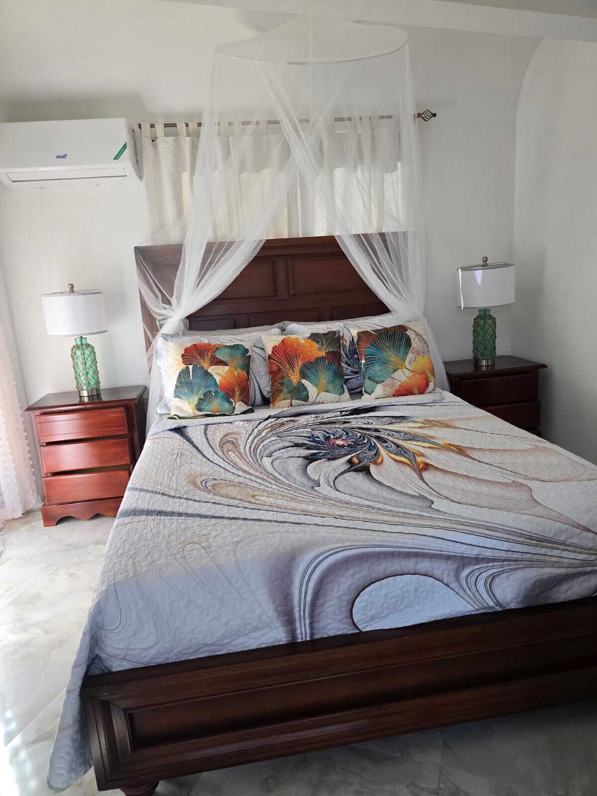 A bed with a canopy, a nightstand with a lamp, and a bedside table with a lamp.