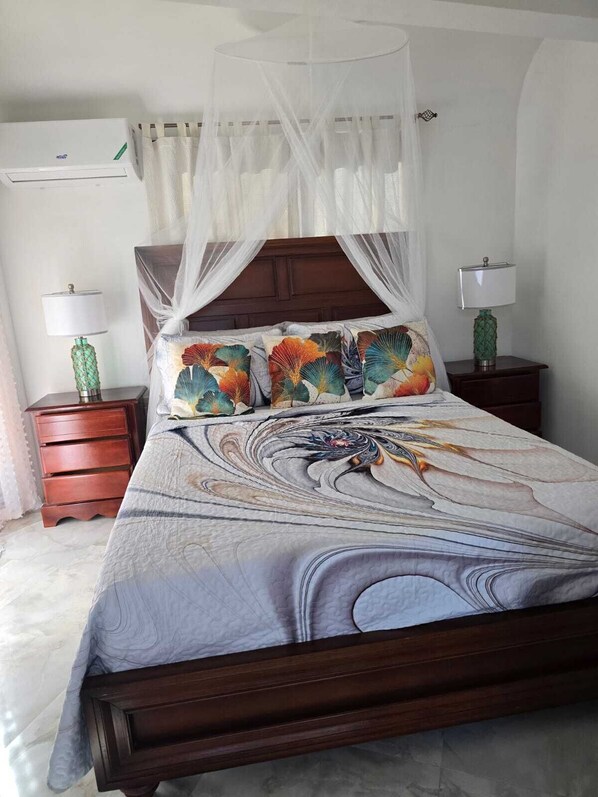 A bed with a canopy, a nightstand with a lamp, and a bedside table with a lamp.