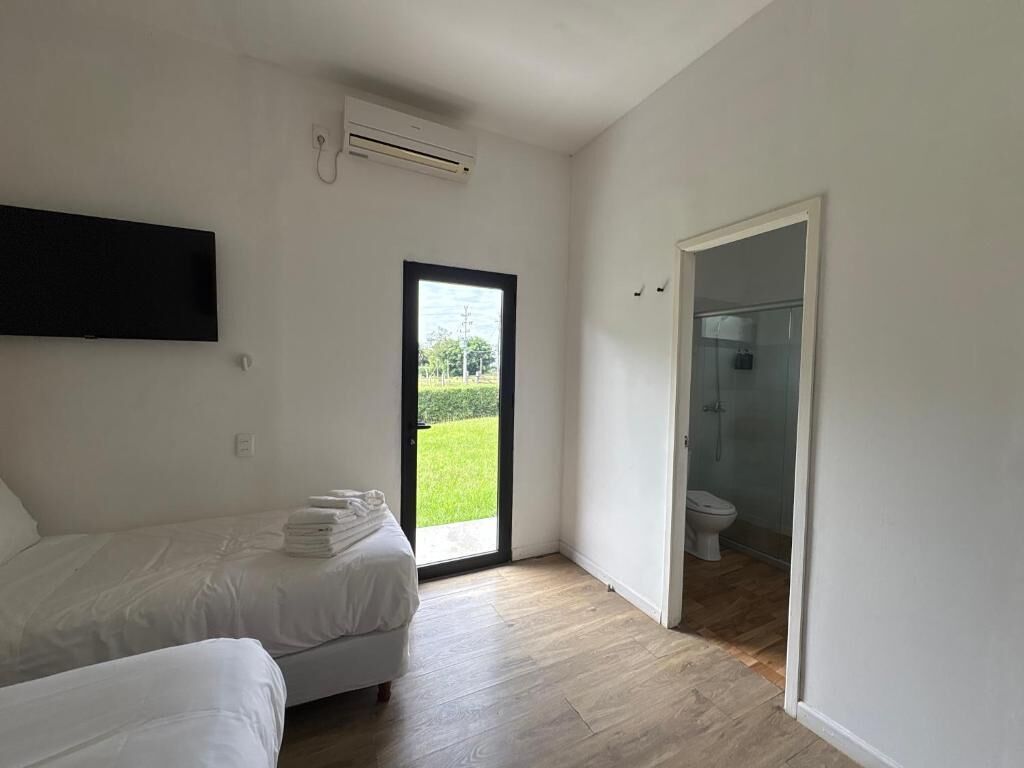 Une chambre comprenant un lit, un téléviseur à écran plat, un appareil de climatisation et une porte donnant accès à une salle de bain.