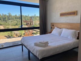 Un dormitorio con una cama grande, vistas al exterior y un cabecero de madera.