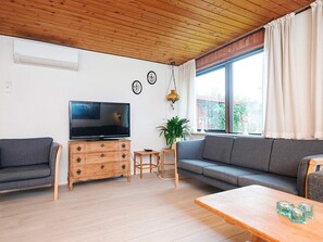 A living room with a television, sofa, wooden cabinet, and a small table. - 10 Person Holiday Home in Herning (Herning)