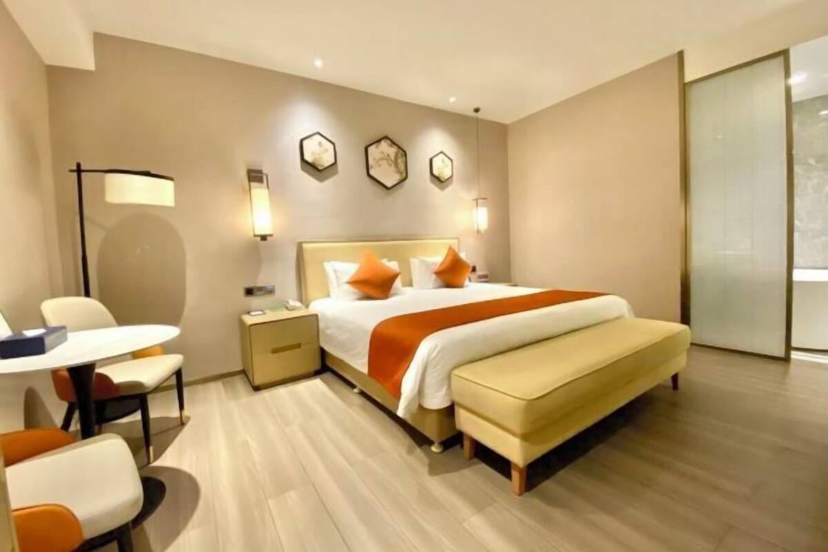 Ein modernes Hotelzimmer mit Bett, Nachttischen, einem Schreibtisch und Stühlen.