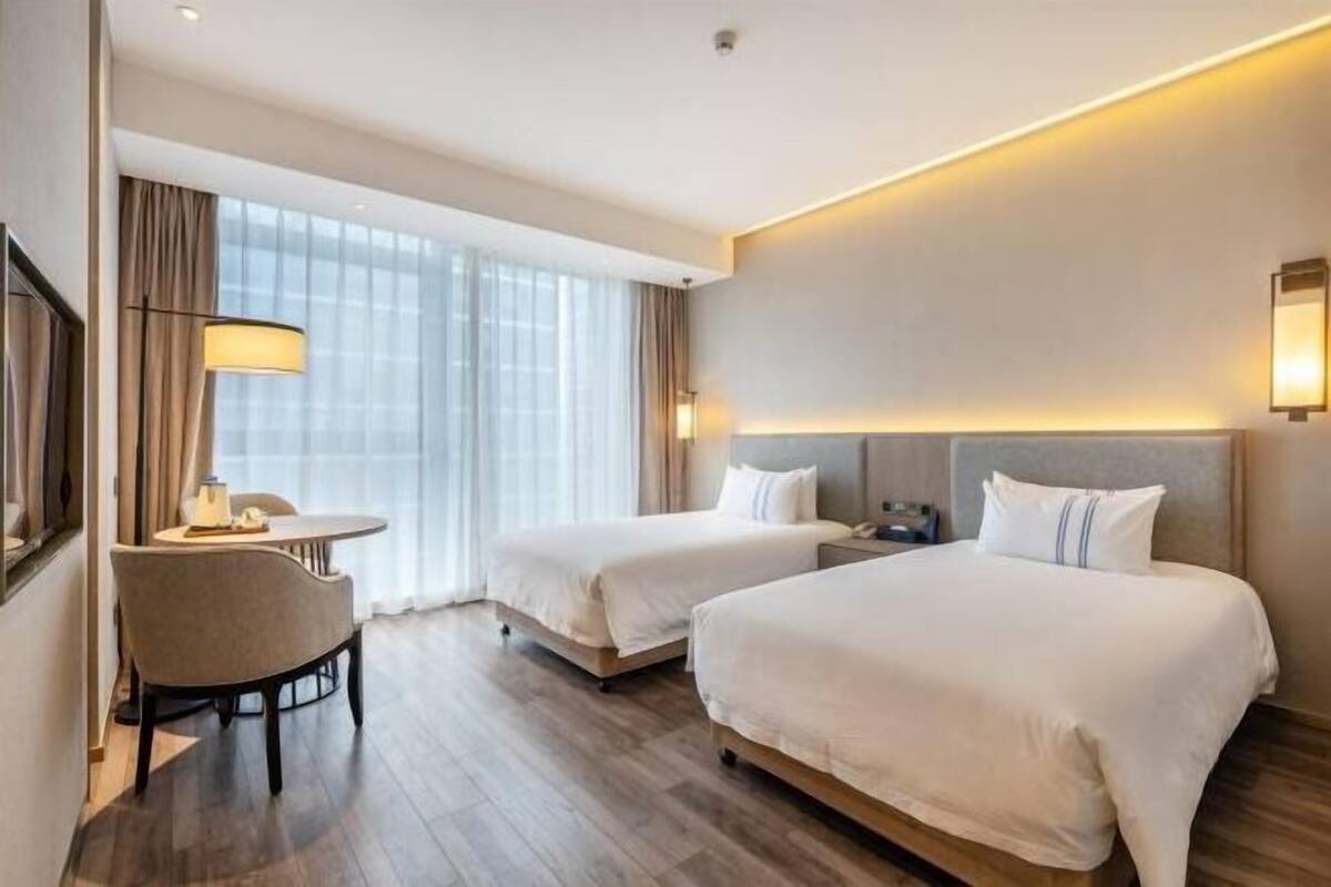 Ein Hotelzimmer mit zwei Betten, einem Schreibtisch und einem Stuhl.