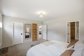 Ein Schlafzimmer mit einem Bett, einer hölzernen Sitzbank, einem Kleiderschrank und einer Tür zu einem Badezimmer.