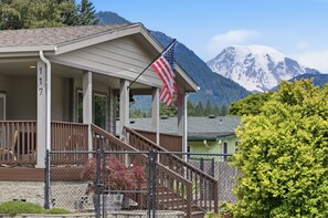 Ein Haus mit Veranda, einer Flagge und einem Berg im Hintergrund.