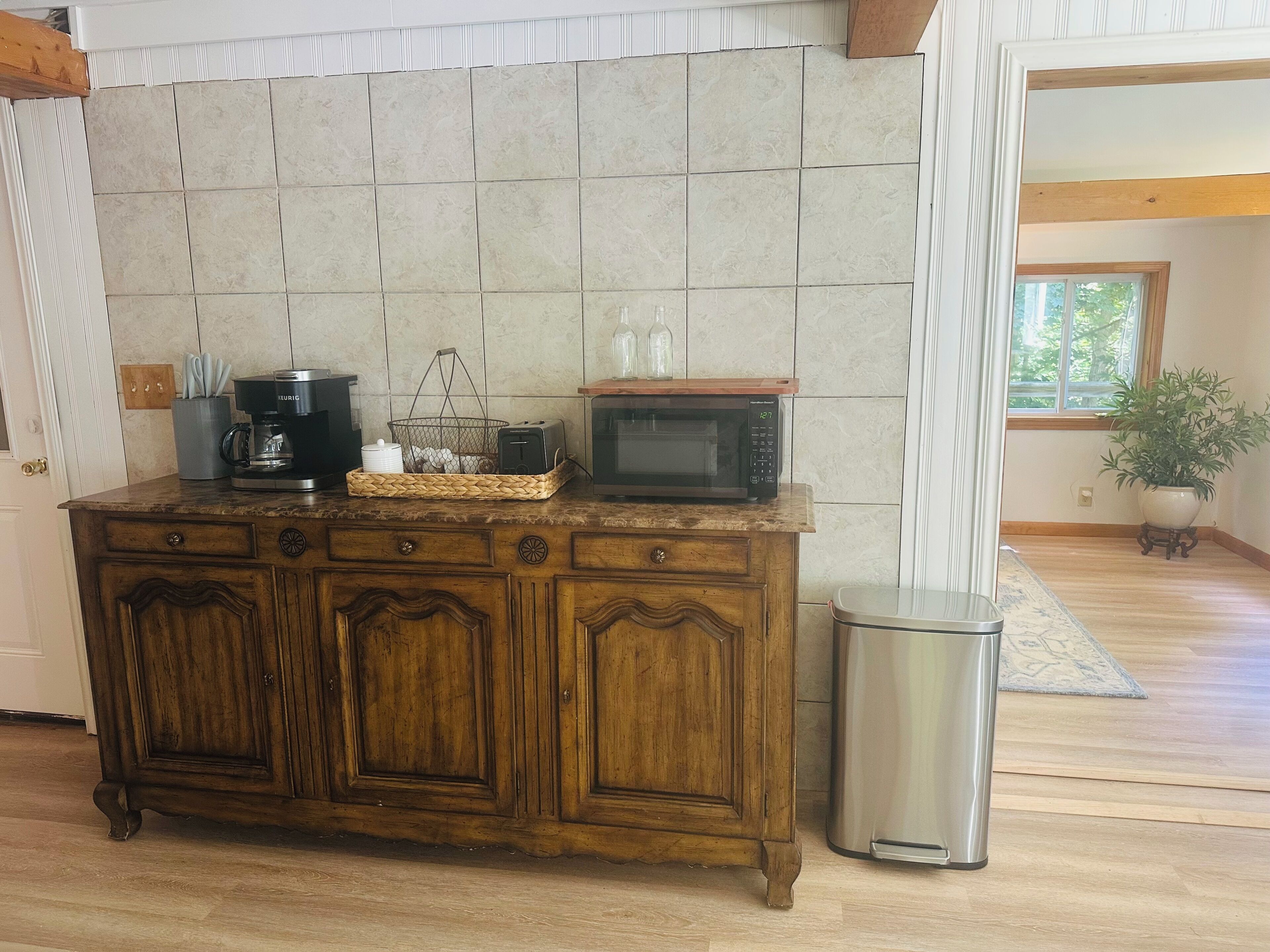 Une cuisine équipée d’un meuble en bois, d’un four à micro-ondes, d’une machine à café et d’une poubelle.