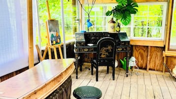 Une terrasse en bois avec un coin bar, une table avec des chaises et une fenêtre donnant sur un paysage verdoyant.
