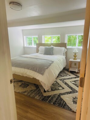 A bedroom with a bed, a nightstand, a lamp, and a window. - Private 2BR Finger Lakes Retreat Near Wineries & Seneca Lake (Hector)