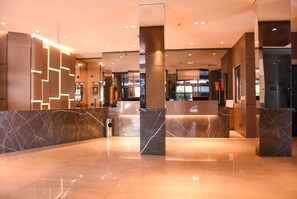 Eine moderne Lobby mit Marmorböden, einem Empfangstresen und einer Glastrennwand.