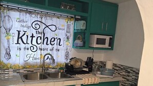 Une cuisine avec des armoires de couleur turquoise, un évier en acier inoxydable, un four à micro-ondes et une cuisinière.