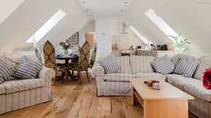 A loft-style apartment with a dining area, a sofa set, a kitchen, and a dining table. - The Coach House - Beautiful 3 Bedroom Home in Oxfordshire (Souldern)