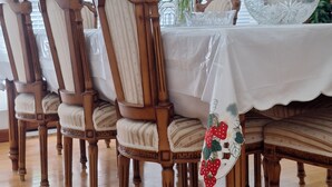 A dining area with wooden chairs, a white tablecloth, and a floral centerpiece.