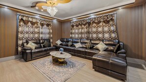 A modern living room with a sectional sofa, a round coffee table, and decorative curtains. - Spacious 6-bedroom house in peaceful Niagara Falls with AC for 22 people sleep (Niagara Falls)