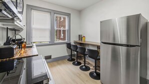 A compact kitchen with a stainless steel refrigerator, a wooden countertop, and three black bar stools. - Spacious 6-bedroom house in peaceful Niagara Falls with AC for 22 people sleep (Niagara Falls)