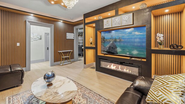 A modern living room with a fireplace, a large TV, and a comfortable seating area. - Spacious 6-bedroom house in peaceful Niagara Falls with AC for 22 people sleep (Niagara Falls)