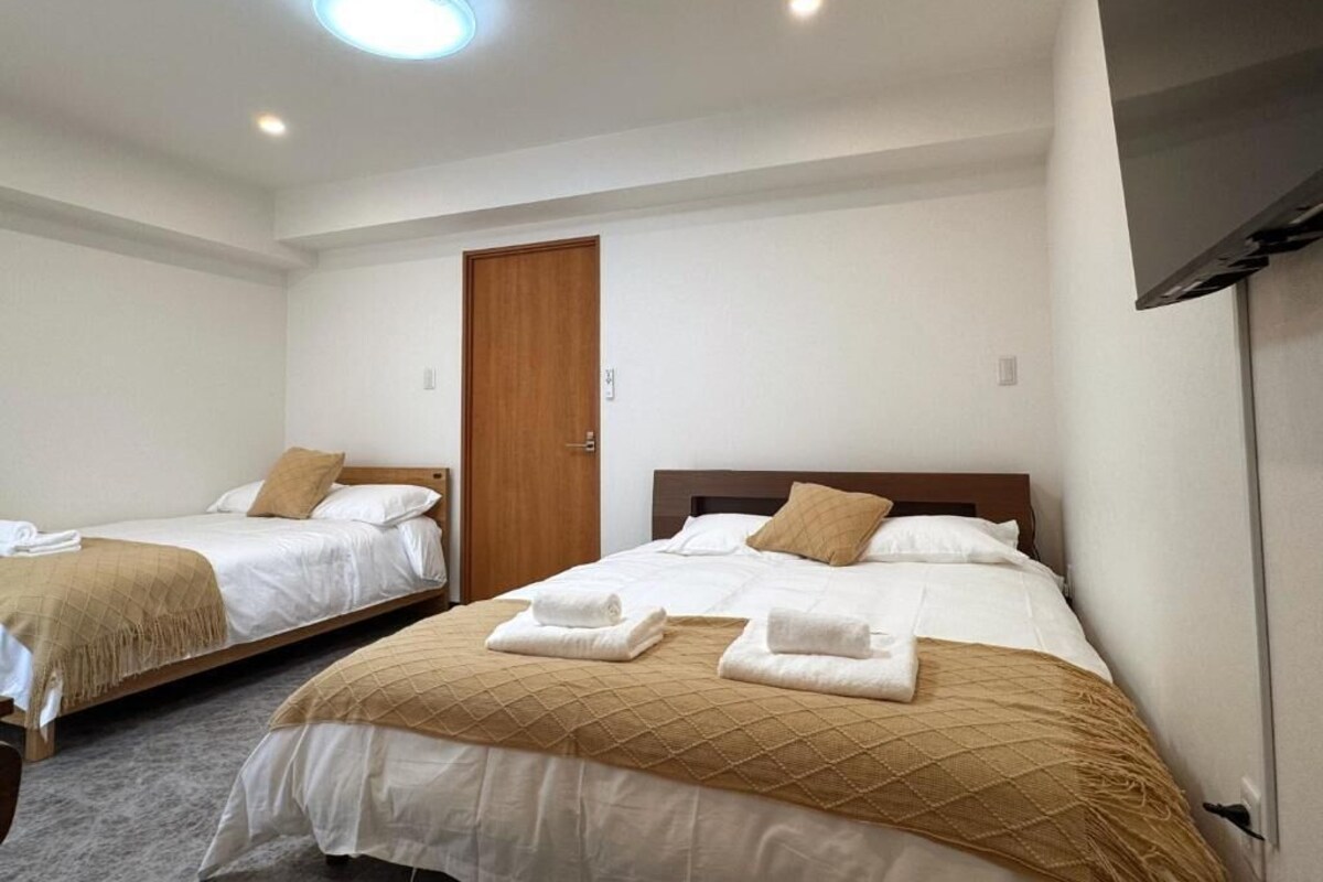 Camera d'albergo con due letti, una porta in legno, una TV a schermo piatto e una luce a soffitto.